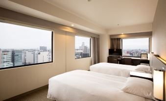 a hotel room with two beds , one on each side of the room , and a view of the city outside the window at Kawasaki Nikko Hotel