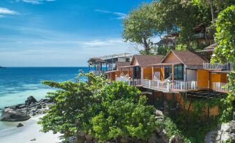 a picturesque beach scene with a wooden house overlooking the ocean , surrounded by lush greenery at Chareena Hill Beach Resort