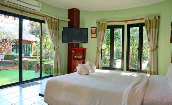 a spacious bedroom with a large bed , a television , and a door leading to a patio at Aurora Resort Chiangdao