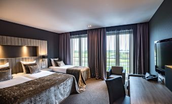 a hotel room with two beds , a desk , and a window overlooking a golf course at Van der Valk Hotel Middelburg