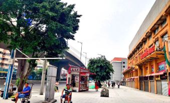There are people walking and standing on a street near an empty bus stop at Tongtong Hotel
