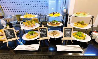 a buffet table with a variety of food items , including salads , fruits , and desserts , displayed on white plates at Rizal Park Hotel