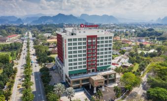 an aerial view of a large hotel building surrounded by trees and mountains , with a highway in the background at Travelodge Ipoh