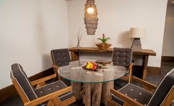 a round dining table surrounded by four chairs , with a vase of flowers placed on the table at Nizuc Resort & Spa