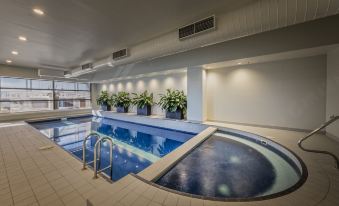 a large indoor swimming pool with a blue and white tiled floor , surrounded by potted plants at PARKROYAL Melbourne Airport