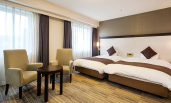 a large bed with white and brown linens is in a room with wooden flooring at Daiwa Roynet Hotel Oita