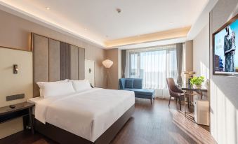 A modern bedroom with large windows features a white bed and a matching chair in the center at Metropolo Jinjiang Hotel (Harbin Haxi High-speed Railway Station Wanda Plaza)