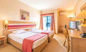 a hotel room with two beds , a desk , and a window , decorated in pink and white colors at Riviera Hotel