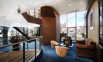 The living area features a spacious room with stairs, chairs, and windows adjacent to it at Prudential Hotel
