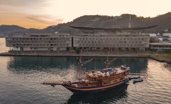 a large ship sailing on a body of water with a building in the background at Meruorah Komodo Labuan Bajo