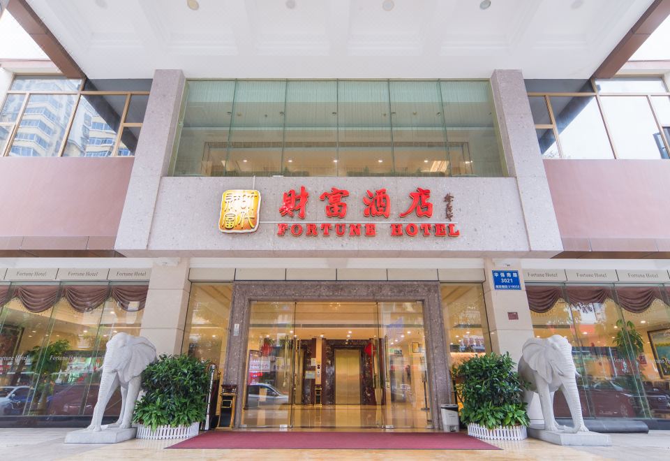 The front entrance of a hotel is adorned with an oriental sign and additional signs at Fortune Hotel