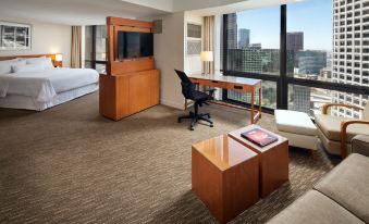 a modern hotel room with a large window , wooden furniture , and a desk with a laptop at The Westin Bonaventure Hotel & Suites, Los Angeles