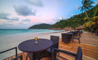 a wooden deck overlooking the ocean , with several chairs and tables set up for outdoor dining at The Taaras Beach & Spa Resort