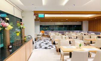 a modern restaurant with white chairs and tables , wooden countertops , and a view of the outdoors at Hotel Fuse Rayong