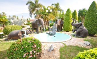 a fountain with three elephant sculptures in the center , surrounded by palm trees and bushes at Tokyo Hotel