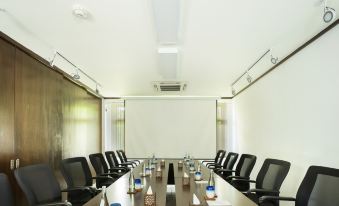 a conference room with a long wooden table , black chairs , and a white screen on the wall at Heritance Aarah-Premium All Inclusive