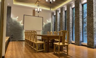 A large room is furnished with wooden tables and chairs, and there is an art piece on the wall at Manyuan Resort Hotel