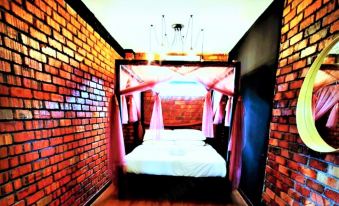 a cozy bedroom with a canopy bed in the center , surrounded by brick walls and wooden flooring at Petak Padin Cottage by The Pool, Kepala Batas Penang