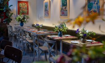 In the dining room, there is a long table set for four people, surrounded by large windows and wood paneling at Peking Yard  Boutique Hotel