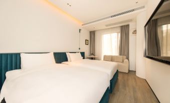 The modern bedroom features a double bed and a large window that overlooks the rest area in a white setting at Autoongo Hotel On the Bund, Shanghai