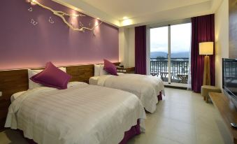 a hotel room with two beds , one on each side of the room , and a view of the ocean at J Resort
