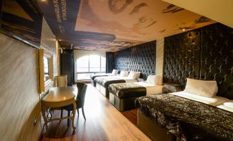 a modern hotel room with black walls , wooden floors , and multiple beds arranged in rows at Arthouse Hotel