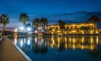 a nighttime scene of a resort with a pool , palm trees , and a building in the background at Hotel Poseidon