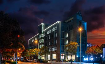 "At night, a large illuminated building with the word ""hotel"" on its front stands prominently" at Shanghai JOYFUL YARD Hotel (Shanghai Pudong Airport Store)