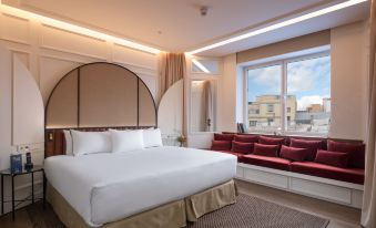 a large bed with white linens is in a room with a window and a red couch at Only You Hotel Valencia