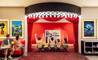 A room is set up for an event, with red and yellow chairs and tables in front at The Universal Studios Grand Hotel