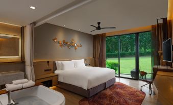 a modern bedroom with a large bed , a bathtub , and a window overlooking a green field at Dusitd2 Khao Yai