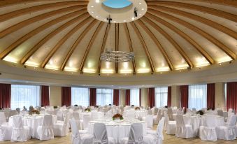 a large , elegant conference room with multiple tables and chairs set up for a formal event at UNA Hotels Expo Fiera Milano