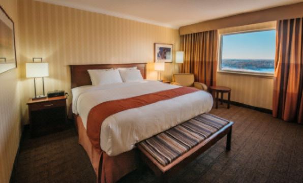 a hotel room with a large bed , a window , and a bench at the foot of the bed at The Explorer Hotel