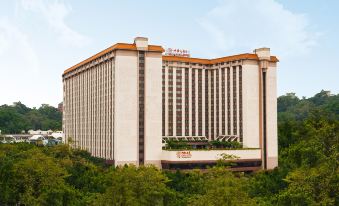 A large building with numerous windows on the side overlooks an office complex in front at China Hotel