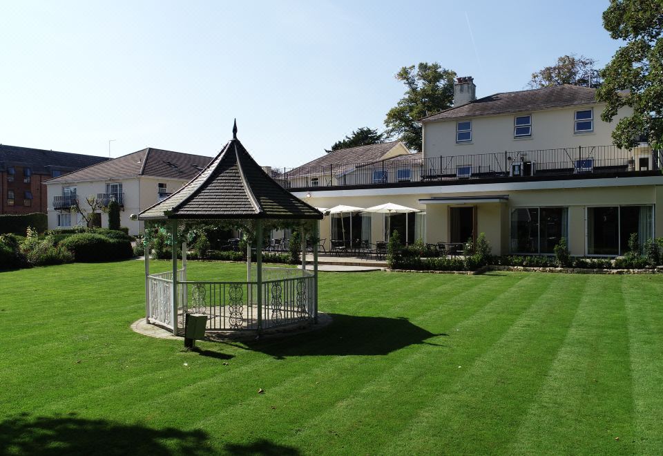 a large white house with a well - maintained lawn and a gazebo in the front yard at Alton House Hotel