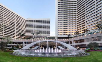 There is a large fountain in front of a group of buildings with water behind them, including one that has an oriental style at LN Garden Hotel Guangzhou