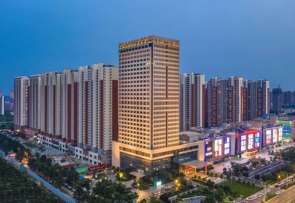 At night, a cityscape is illuminated by tall buildings, with an office tower standing prominently in the center at Ramada by Wyndham Heze