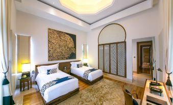 a hotel room with two twin beds , a large painting on the wall , and a rug at Banyan Tree Tamouda Bay