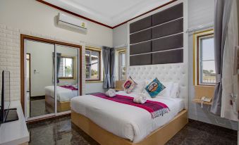 a modern bedroom with a white bed , black headboard , and large windows , along with other furniture such as a mirror and lamp at Infinity See Sun Resort