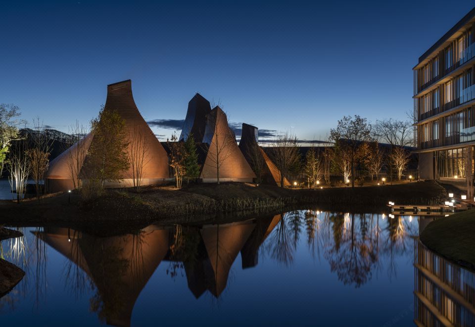 At night, a cityscape with illuminated buildings and water in the foreground at Hoshino Resorts KAI Poroto