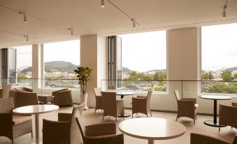 a modern , empty restaurant with large windows offering views of the city and mountains , featuring comfortable seating arrangements and a dining table at Lahan Hotel Jeonju