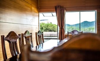 a dining room with a wooden table and chairs , surrounded by windows overlooking the outdoors at Baan Tah On The Sea