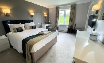a large bed with white linens is in a room with gray walls and a window at Lancaster House Hotel