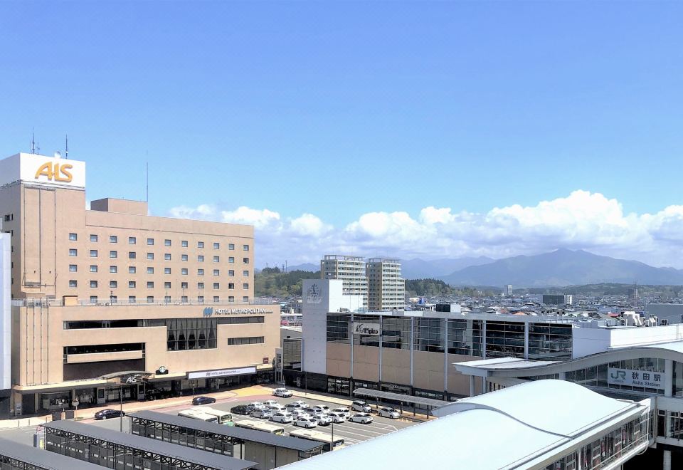 a cityscape with a large building in the background and a parking lot in the foreground at Hotel Metropolitan Akita