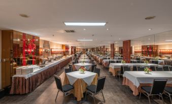 a large dining room filled with tables and chairs , where people are seated and enjoying their meals at M Hotels