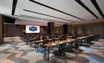 The large conference room is an empty meeting space with rows of tables in front of the center at Hampton by Hilton Beijing Guomao CBD