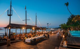 A beachfront restaurant with people in front and water behind it during dusk at Aureum Palace Hotel & Resort, Ngapali