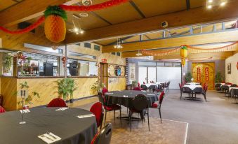 a large room with several tables and chairs , each table has a red pineapple decoration at The Wine Vine Hotel