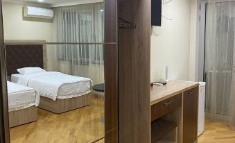 a hotel room with two beds , a desk , and a mirror , reflecting the room 's interior at Grand House hotel & zipline