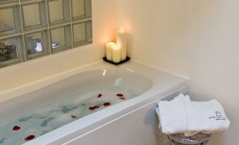 a bathtub filled with water , surrounded by various items such as towels , candles , and flowers at Avenue Boutique Hotel